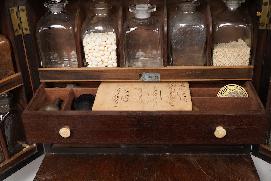 A 19th century mahogany apothecary cabinet, interior with fitting compartments containing twenty-one glass bottles, most with stoppers, five drawers with ivory knobs containing a miniature pestle and water, mixing glasse